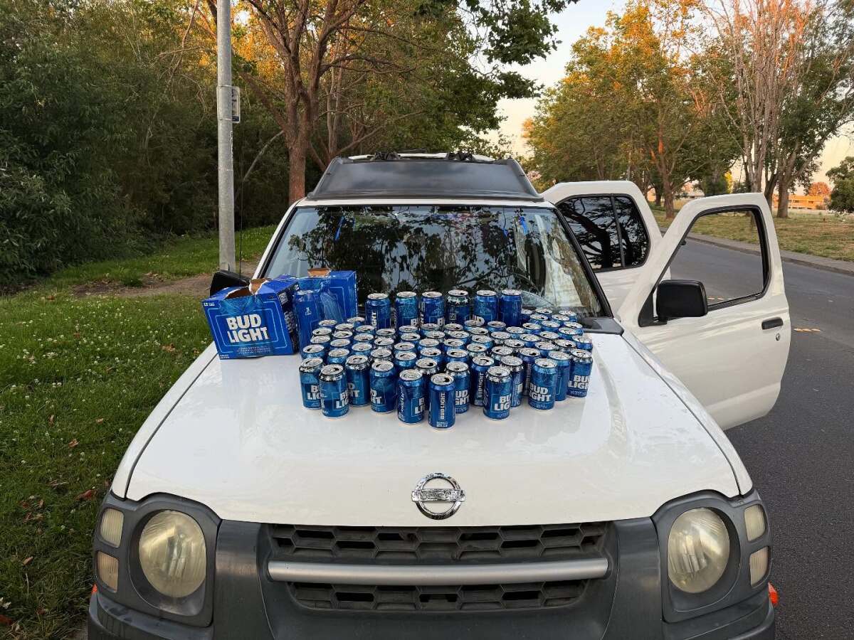 Beer cans arranged on the hood of a car.