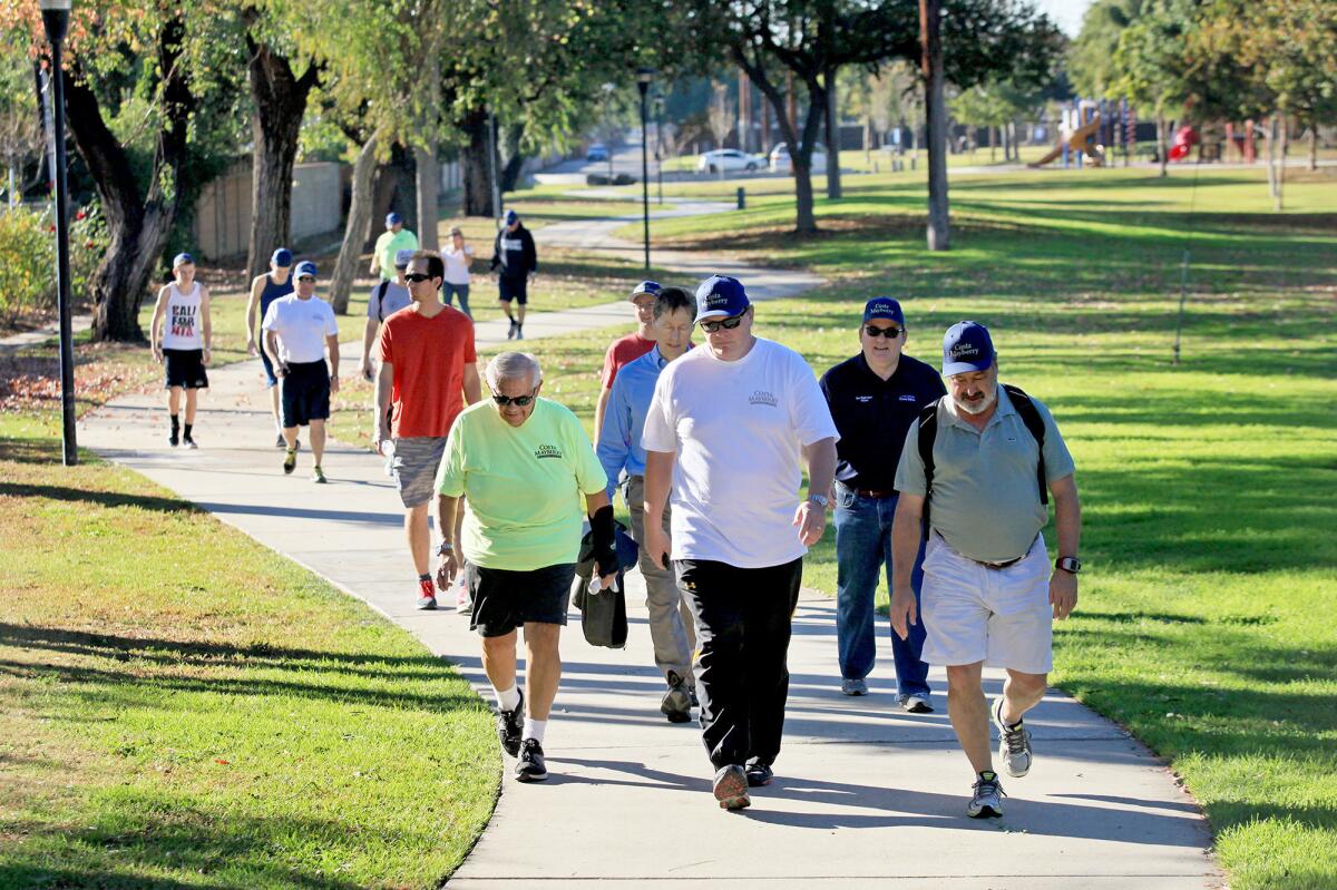 Mayor Pro Tem Steve Mensinger, foreground center, and a dozen other participants stroll through Gisler Park in Costa Mesa on New Year's Eve. The group completed a 5.38-mile walk that started at the Diego Sepulveda Adobe in Estancia Park and ended at Plaza Tower, near South Coast Plaza.