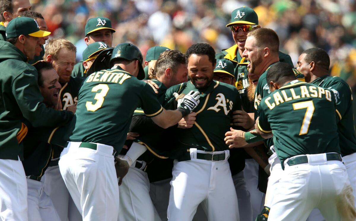Coco Crisp, center, is mobbed by his Athletics teammates after hitting a walk-off single to score Alberto Callaspo from second base and give Oakland a 2-1 win Saturday over the Boston Red Sox.