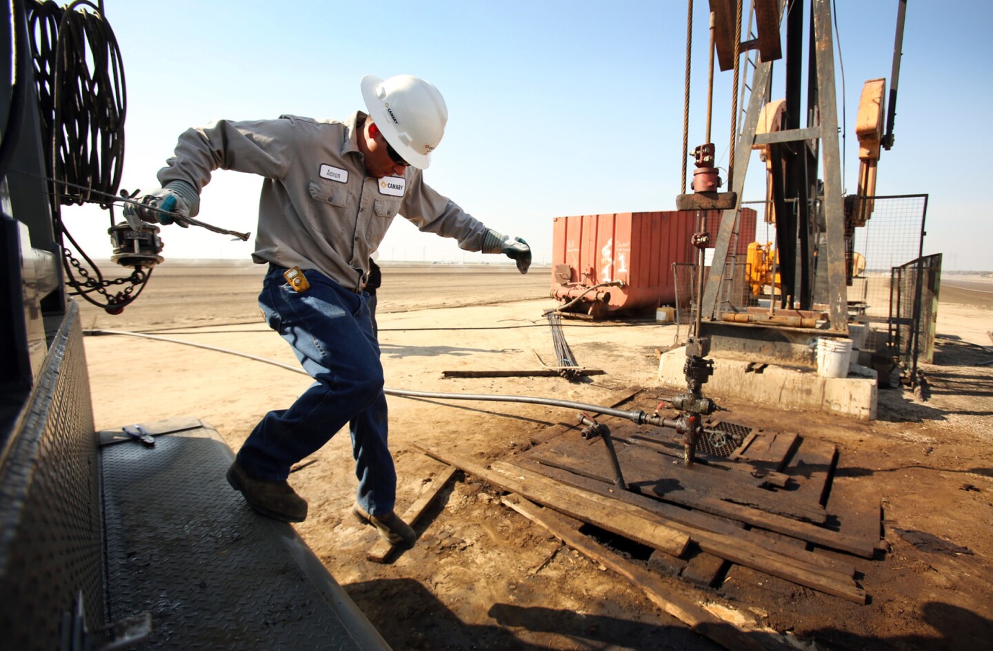Aaron Kent, an employee of oil services firm Canary, works at an oil rig pump jack near Bakersfield in March 2013. Some 12,000 people are on oil and gas extraction and well-drilling payrolls in the area.