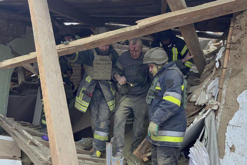 In this photo provided by the Ukrainian Emergency Service, emergency workers help a wounded man after a residential houses were badly damaged in a Russian missile attack, near Kryvyi Rih, Ukraine, Monday, Jan. 8, 2024. (Ukrainian Emergency Service via AP)