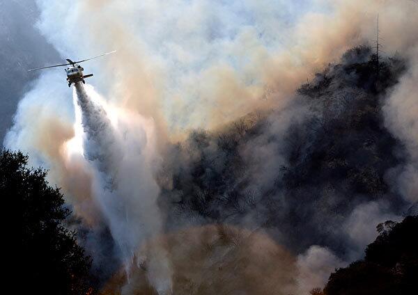 A helicopter makes a drop over a brush fire north of La Canada Flintridge on Wednesday. The blaze broke out about 3:20 p.m. near mile marker 29 on Angeles Crest Highway. Smoke from this blaze and another in the Angeles National Forest fouled Southland skies and prompted health officials to warn those with respiratory problems to stay indoors.