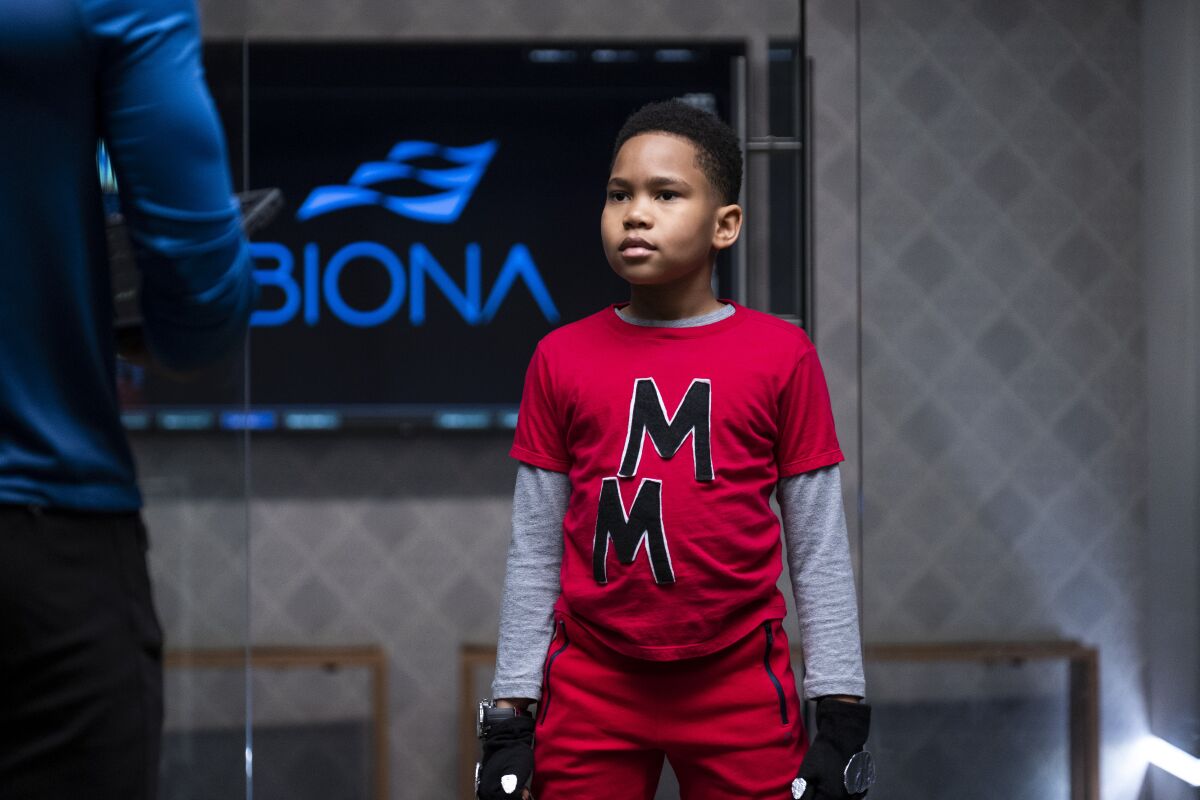 A young boy in a red shirt and pants combo emblazoned with double MMs