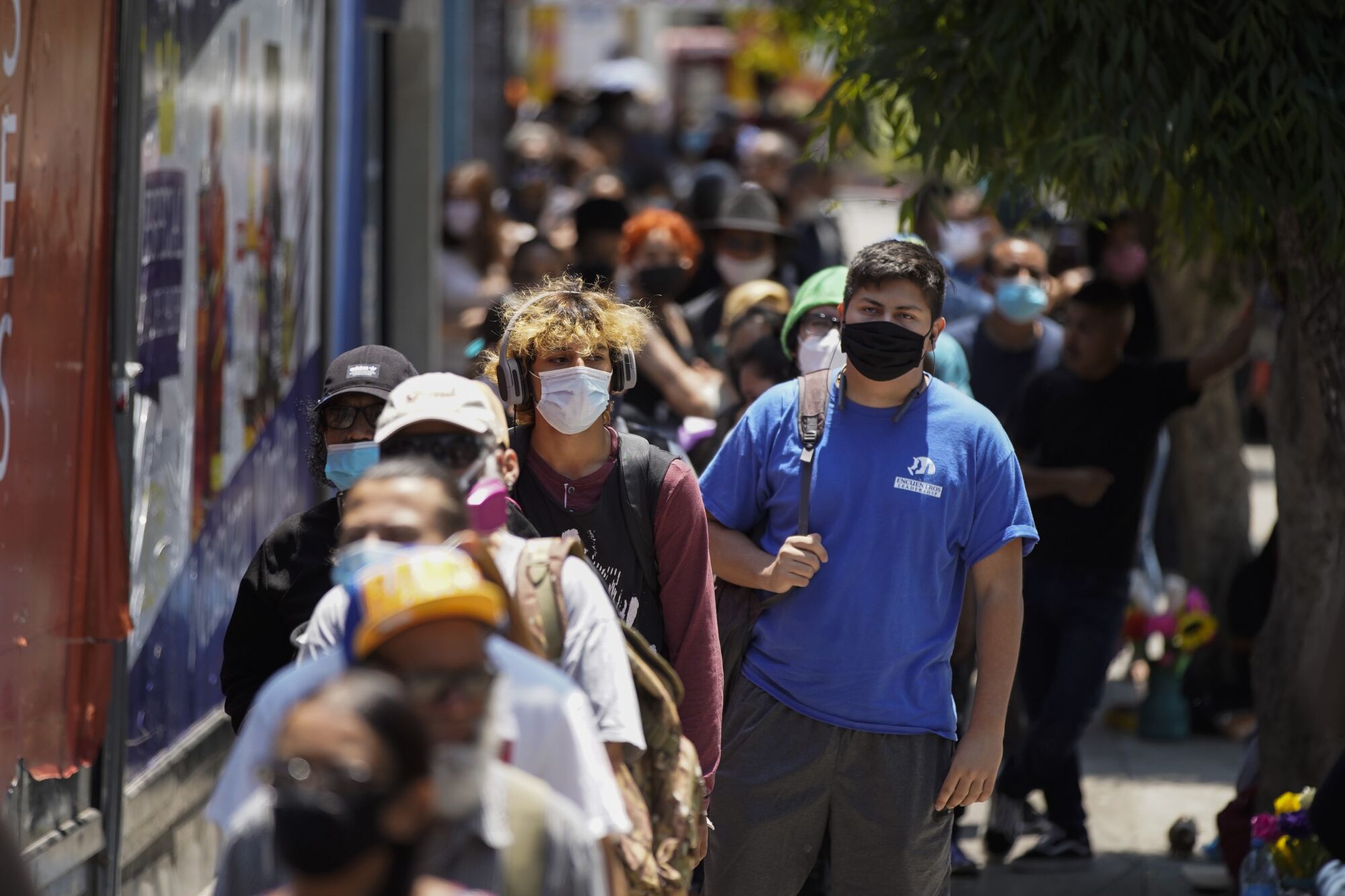 Mask-wearing people wait in a long line outside at the San Ysidro Port of Entry to cross from Tijuana