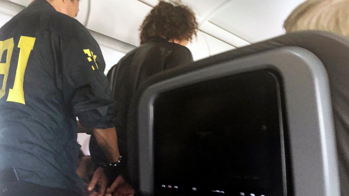 In a photo provided by a passenger, a man is escorted off an American Airlines flight upon arrival in Honolulu.