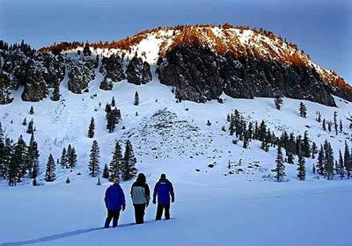 As the sun comes up on an early-morning snowshoe hike near Mammoth Mountain, granite hilltops are painted golden orange.