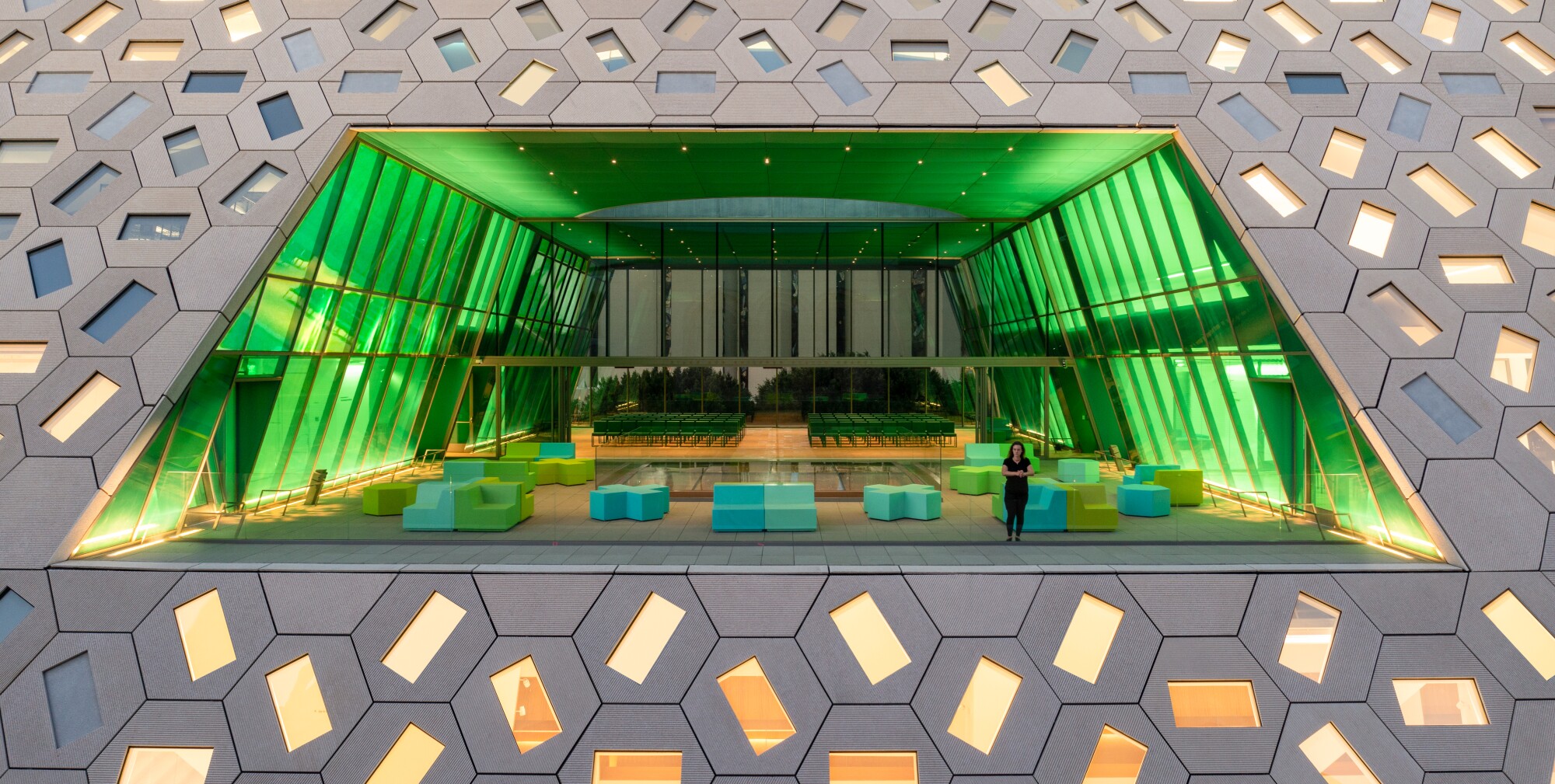 A view of an open air terrace rendered in shades of electric green and framed by a hexagonal window.