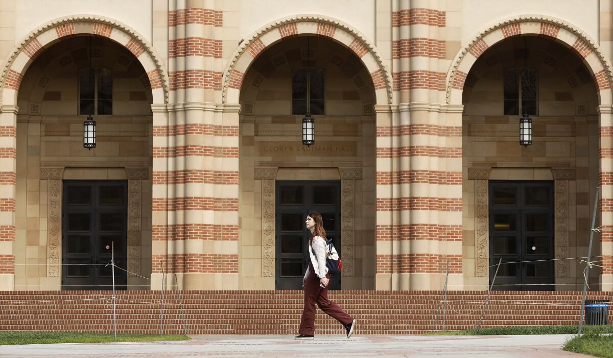 A pedestrian walks past arches on the UCLA campus.