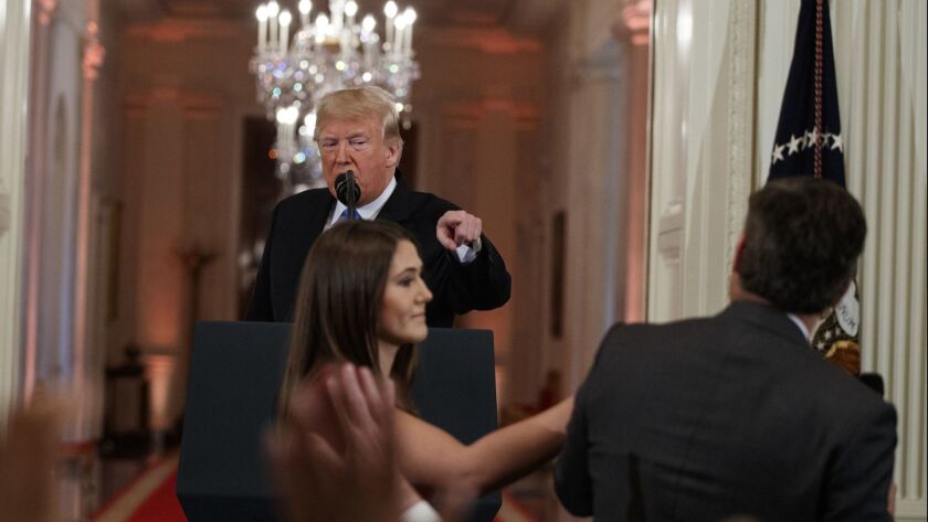 President Donald Trump looks on as a White House aide attempts to take away a microphone from CNN journalist Jim Acosta during a news conference in the East Room of the White House, on Wednesday, Nov. 7 in Washington.