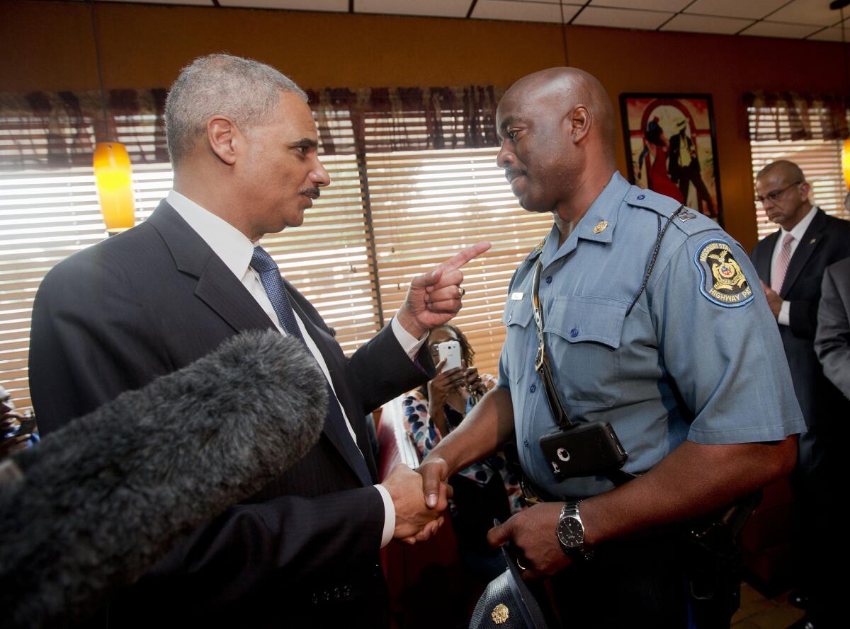 Atty. Gen. Eric H. Holder Jr. talks with State Highway Patrol Capt. Ron Johnson in Florissant, Mo., in August 2014. The Justice Department plans to open an investigation into the practices of the Ferguson, Mo., police department after the fatal shooting of Michael Brown, 18.