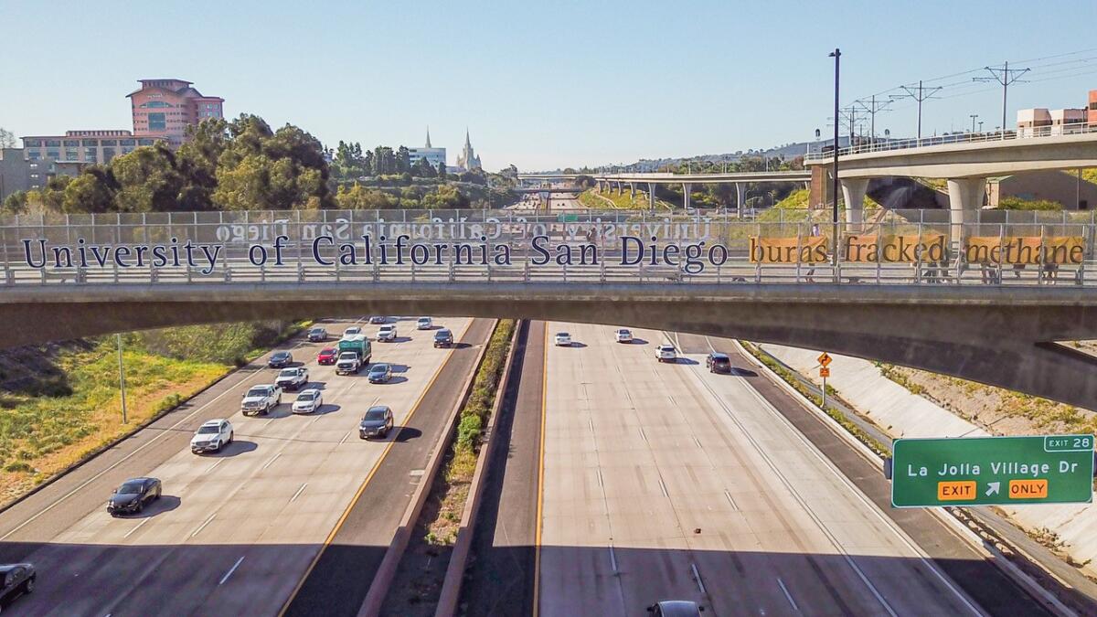 A banner hangs over Interstate 5 opposing UC San Diego's use of fossil fuels to generate electricity.