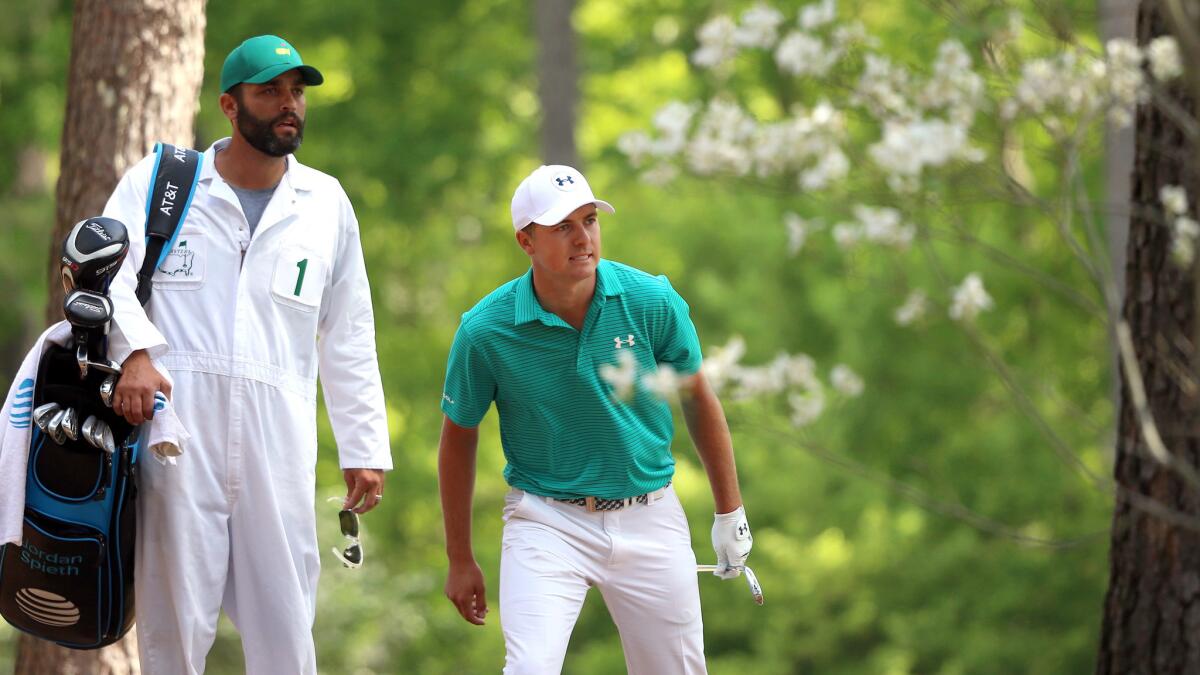 Jordan Spieth and caddie Michael Greller watch Spieth's second shot from the woods along the 11th fairway during the first round of the Masters on Thursday at Augusta National Golf Club.