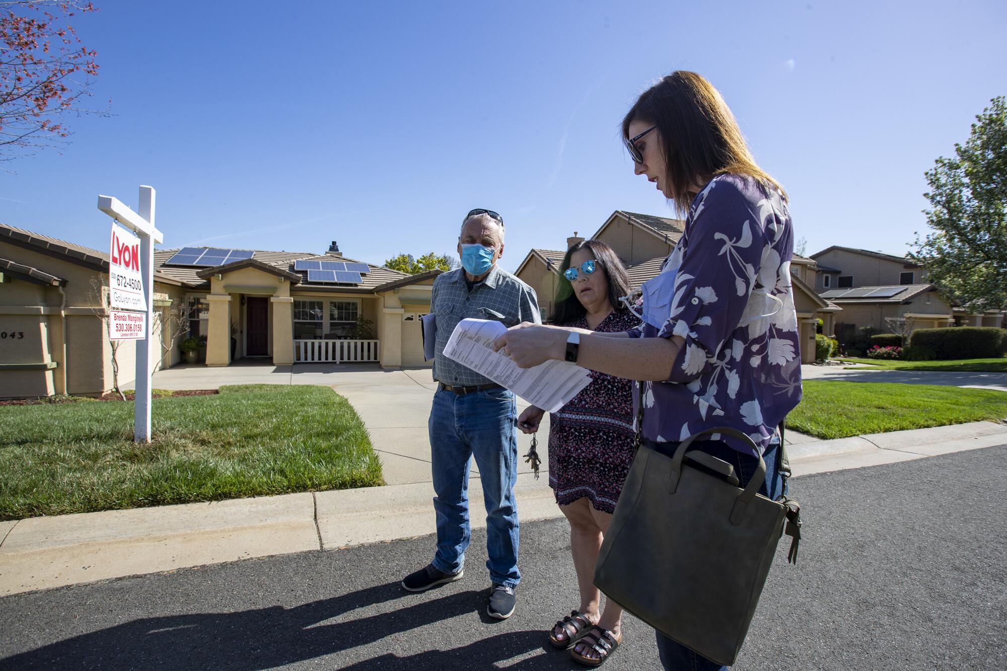 Real estate agent Morgan Larson, right, prepares to show a home to prospective buyers Gary and Karen Edmondson.