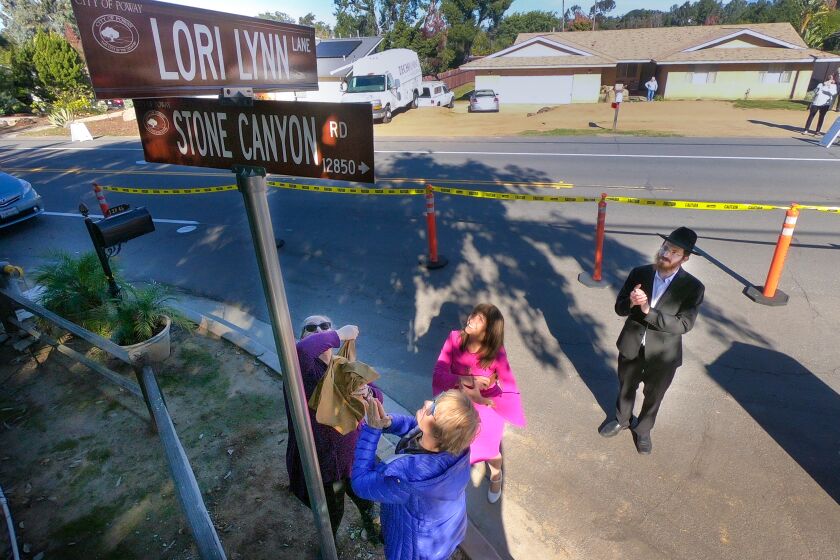 Rabbi Mendel Goldstein of Chabad of Poway, right, looks on, as Jane Cohen, left, Lidia Kotlyar, foreground, and Roneet Lev, friends of Lynn Gilbert-Kaye who was killed in April, on the last day of Passover when a gunman opened fire killing Gilbert-Kaye and injuring several others in the Chabad of Poway synagogue, unveil the street sign, Lori Lynn Lane at the intersection of Stone Canyon Road, December 20, 2019 in Poway, California. Rabbi Mendel Goldstein's father, Rabbi Yisroel Goldstein, now the rabbi emeritus at Chabad of Poway was shot in the hands during the attack.
