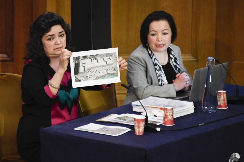 FILE - Witness Qelbinur Sidik, left, shows a picture purported to be of a detention facility, to the Panel of the independent Uyghur Tribunal during the first session of the hearings in London, June 4, 2021. Sidik will be among the witnesses Thursday, March 23, 2023, as a special House committee focused on countering China shines a light on human rights abuses in the country. Sidik is a member of China's ethnic Uzbek minority who was forced to teach Chinese in separate detention facilities for Uyghur men and women. (AP Photo/Alberto Pezzali, File)