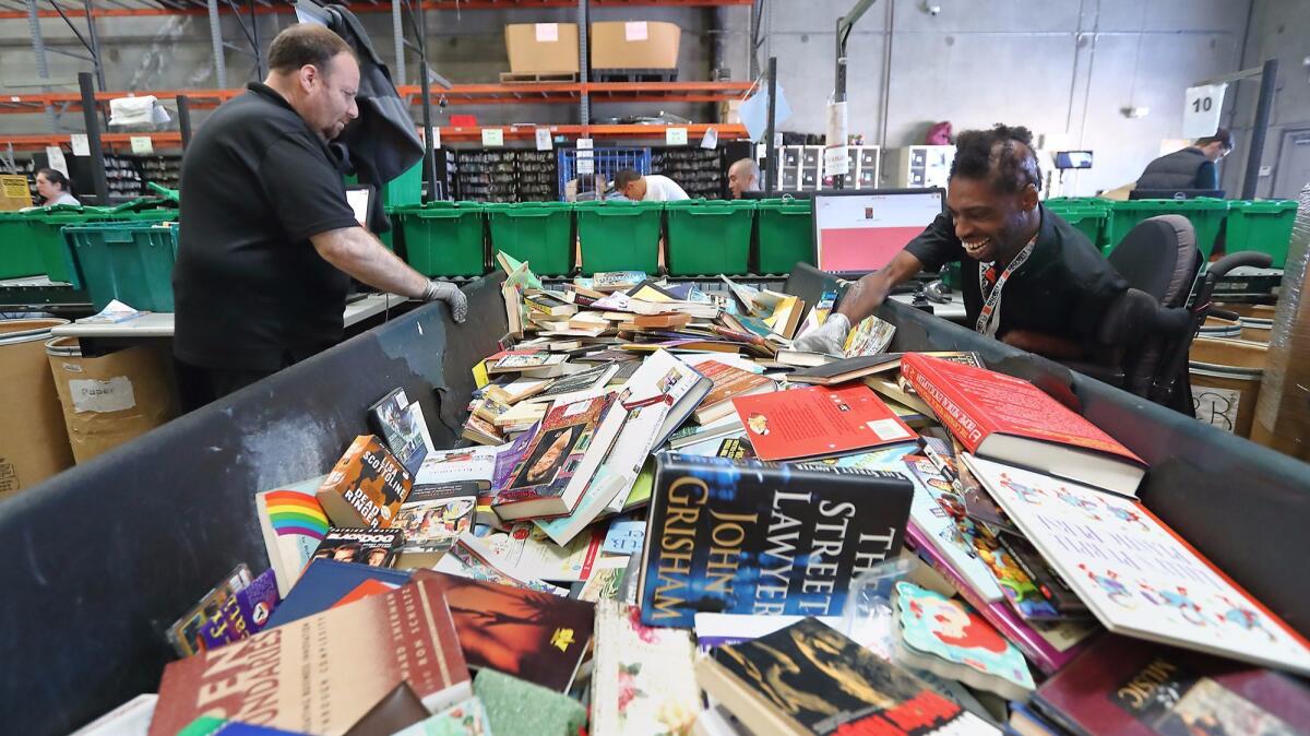 Program participants James Estis, Jr., right, and Robert Rose sort through and categorize book donations at a Goodwill of Orange County warehouse in Santa Ana.