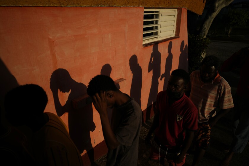 Las sombras de los migrantes haitianos se proyectan en una pared mientras esperan recibir alimentos 