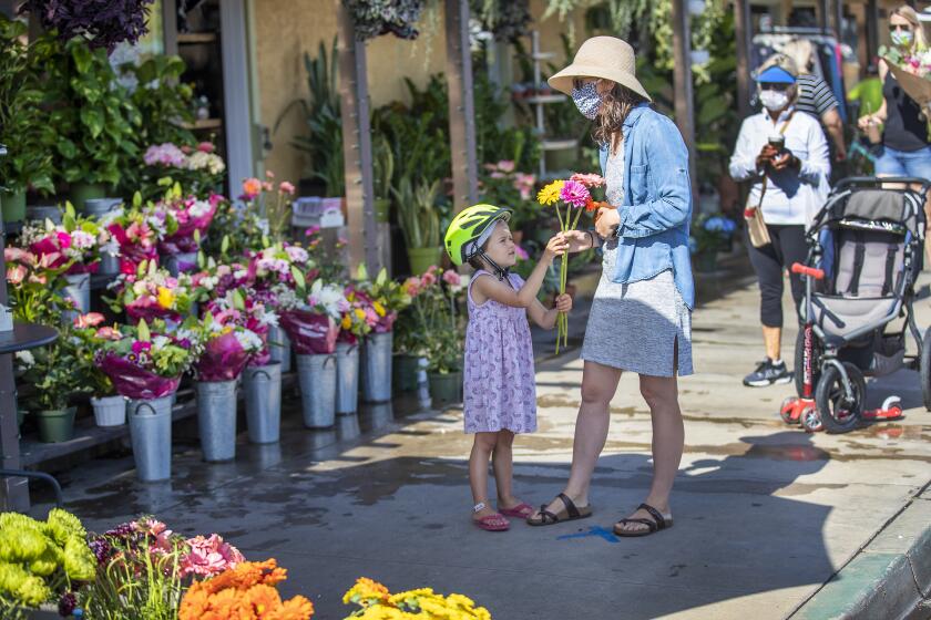 SEAL BEACH, CA -- FRIDAY, MAY 8, 2020: Christina Dagle, center, and her daughter Eleanor Eades, 4, of Seal Beach, wait in line six feet apart from others to buy flowers for a friend from Devynn's Garden in Seal Beach, CA, on May 8, 2020. Some businesses are reopening under a relaxation of the state's stay at home order. Bookstores, music stores, toy stores, florists, sporting goods retailers, clothing stores and others can reopen for pickup and curbside service. (Allen J. Schaben / Los Angeles Times)