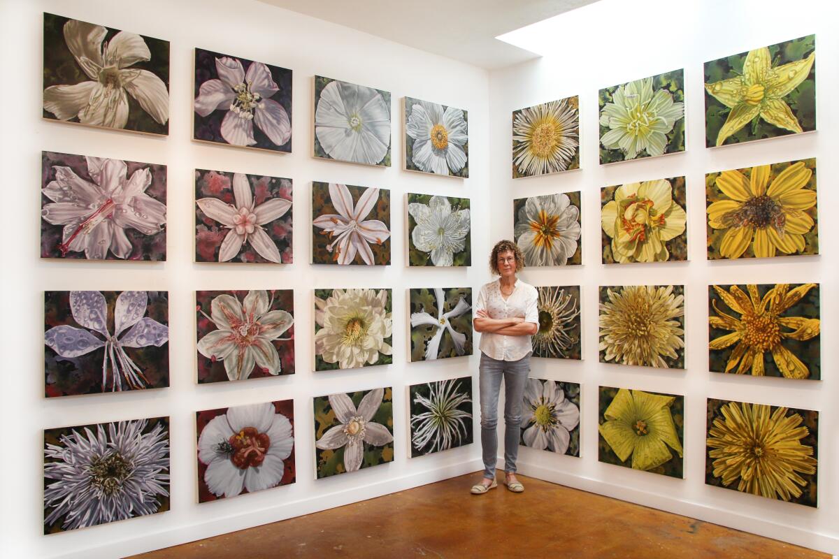 Gail Roberts standing amid her paintings at Quint Gallery.