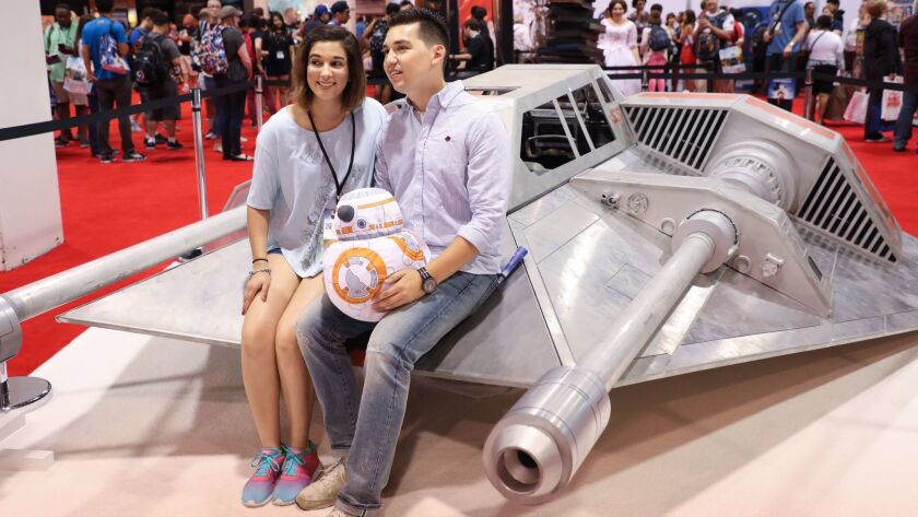 Disney fans pose with a snowspeeder movie prop from the Star Wars films during the D23 Expo in Anaheim. The fan event focuses its activities around the Disney, Star Wars and Marvel franchises.
