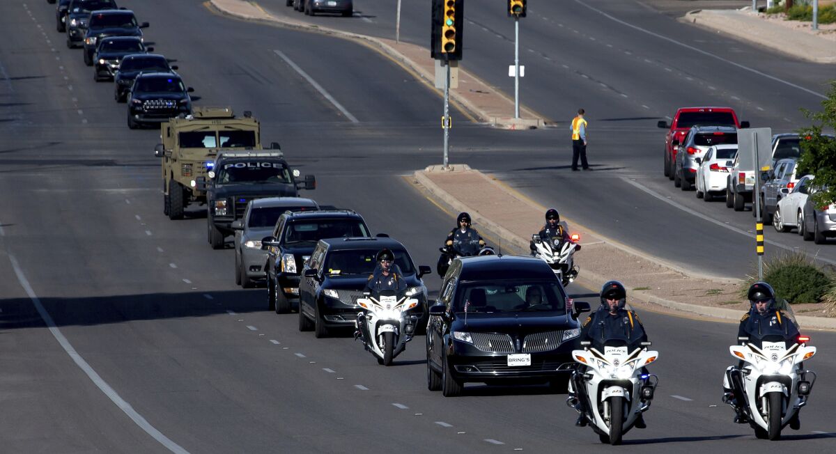 After departing from Bring's Broadway Chapel, a hearse and law enforcement procession for Drug Enforcement Administration Supervisory Special Agent Michael G. Garbo travels down E. Broadway Blvd. in Tucson, Ariz. on Friday, Oct. 8, 2021. Garbo, a federal agent shot and killed while questioning a passenger on an Amtrak train in Arizona, was remembered Friday as a venerated leader and mentor with an unparalleled work ethic. (Rebecca Sasnett/Arizona Daily Star via AP)