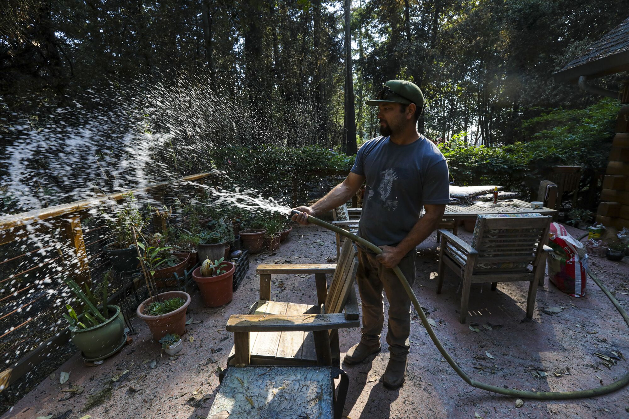 Jonah Torres, a cannabis distributor, waters plants on a patio of an evacuated neighbor.