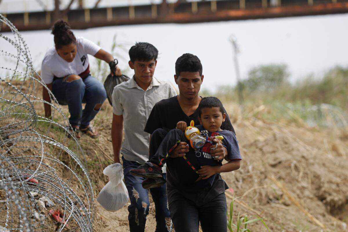 Young migrants walk past razor wire