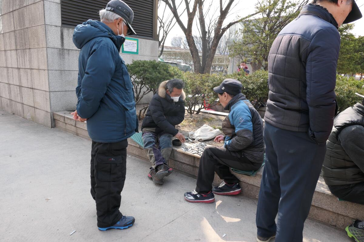 People at Jongmyo Park in Seoul, including two playing a game of Go.