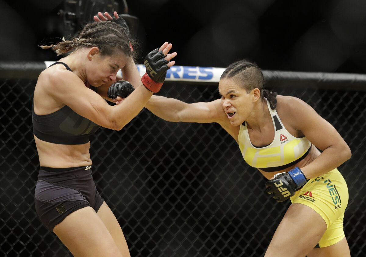 Miesha Tate, left, takes a hit from Amanda Nunes during their bout at Ultimate Fighting Championship's Saturday night event in Las Vegas.