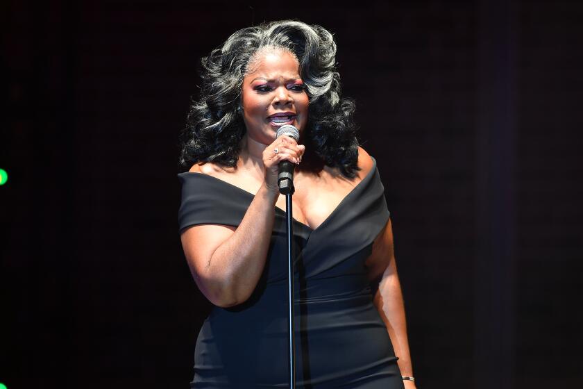 Comedian Mo'Nique, in black, off-the-shoulder dress, performs onstage