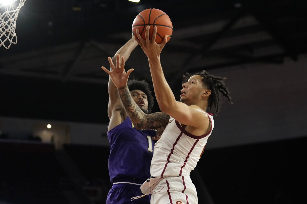 USC guard Tre White, right, drives past Washington forward Keion Brooks during the second half of the Trojans' win Saturday.