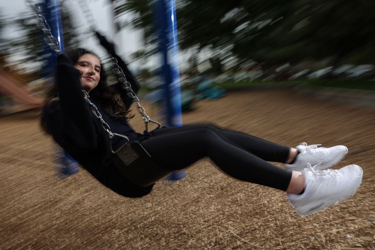 A young woman on a playground swing.