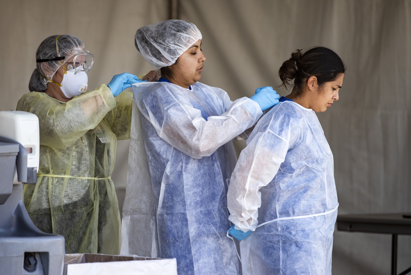 INDIAN WELLS, CA - MARCH 24, 2020: Riverside County medical personnel help each other with their PPE's at a drive-though coronavirus testing facility for Coachella Valley residents in the parking lot of Southwest church on March 24, 2020 in Indian Wells, California. The testing facility is open Tuesday - Saturday.(Gina Ferazzi/Los AngelesTimes)