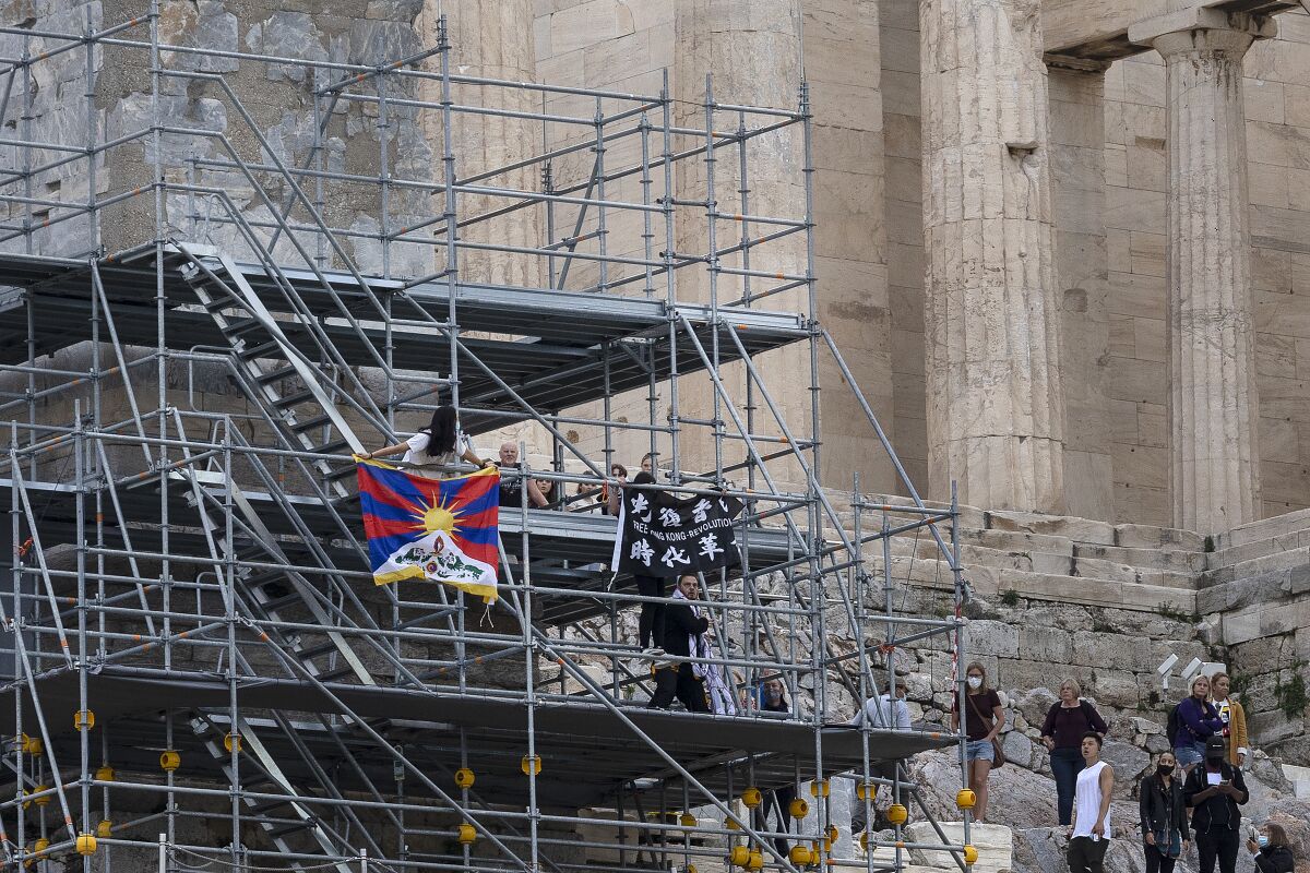 Protesters raise a Tibetan flag and a banner from scaffolding at the Acropolis hill, in Athens, Greece, Sunday, Oct. 17, 2021. Three people attempted to hang a banner from the Acropolis in Athens Sunday morning in protest at the upcoming Beijing Winter Olympics but were arrested before completing their mission. (AP Photo/Yorgos Karahalis)
