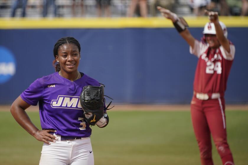 CORRECTS TO FIFTH INNING NOT SECOND INNING - James Madison starting pitcher Odicci Alexander (3) stands in the pitching circle as Oklahoma's Jayda Coleman (24) celebrates at second base behind her after hitting a double in the fifth inning of an NCAA Women's College World Series softball game Monday, June 7, 2021, in Oklahoma City. (AP Photo/Sue Ogrocki)