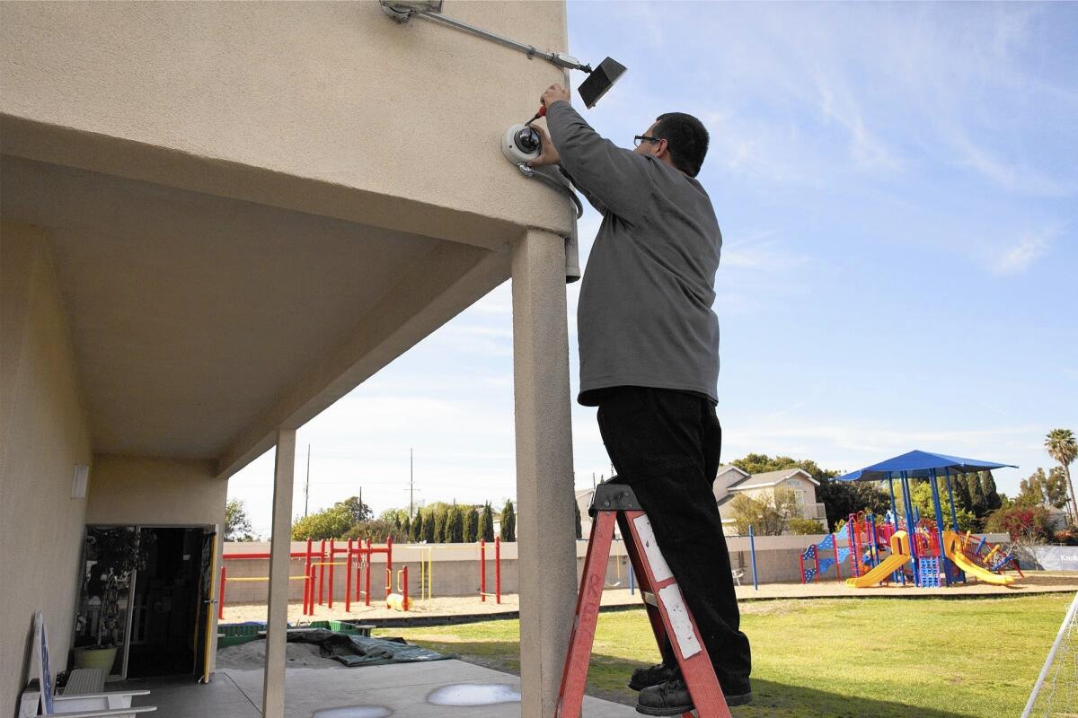 A contractor installs a new closed-circuit camera at Christ Lutheran Church and School in Costa Mesa. Added security measures are part of the church's ongoing renovations.