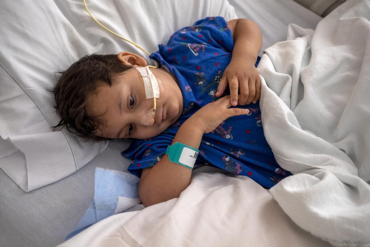 A boy in a hospital bed with a tube connected to his nose