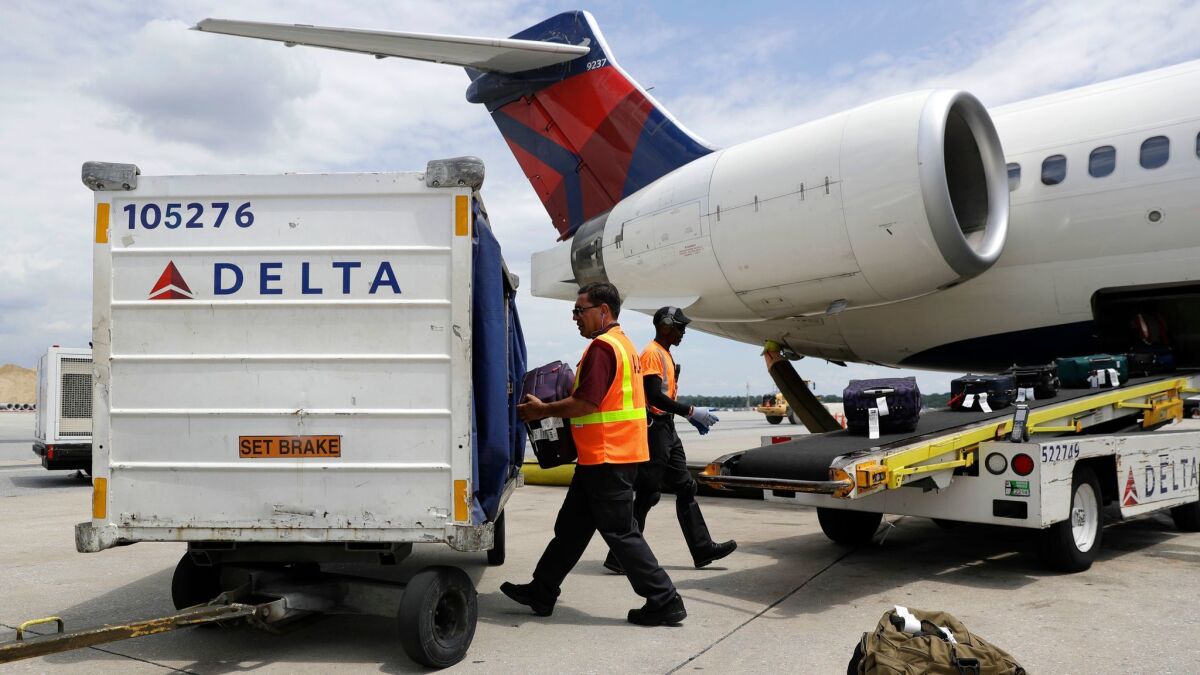 Workers unload baggage from a Delta Air Lines flight at Baltimore-Washington International Thurgood Marshall Airport.