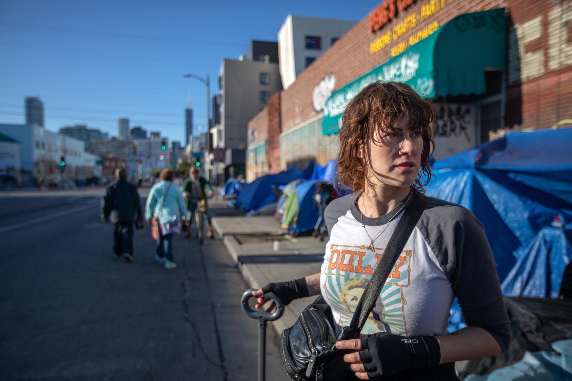 A woman next to a row of tents in a city