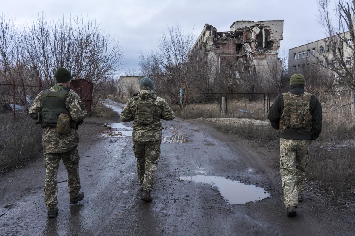 Ukrainian soldiers walk past destroyed buildings in Marinka, Ukraine.