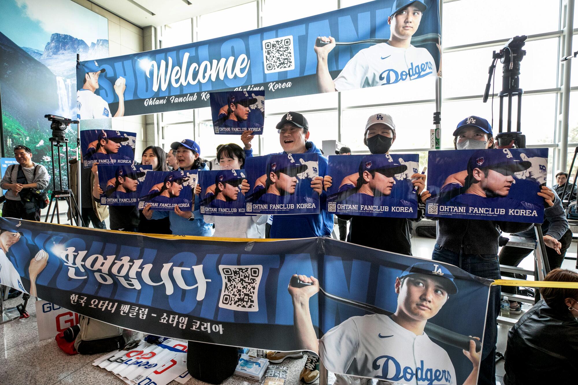 Lee Jae-ik and other Shohei Ohtani fans line up with banners at an airport.