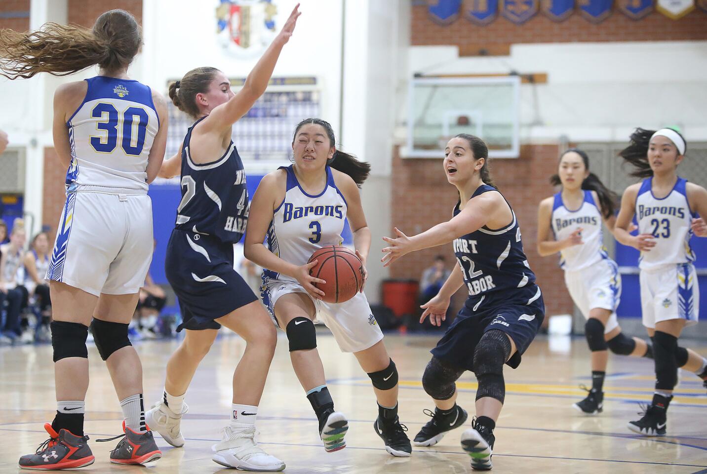 Fountain Valley High's Megan Lai drives to the basket and scores between Newport Harbor's Emma Fults, left, and Selena Muller during a Wave League girls' basketball game on Tuesday.