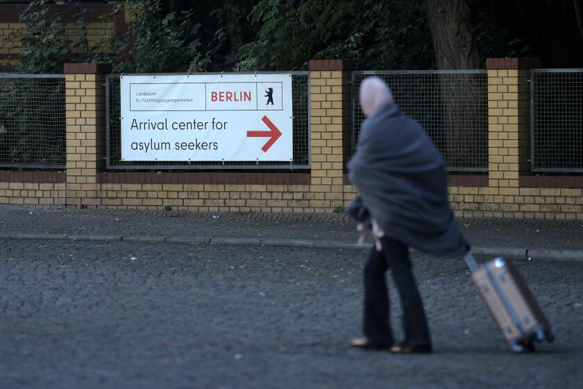 A woman with a trolley leaves the central registration center for asylum seekers in Berlin, Germany, Tuesday, Sept. 26, 2023. Across Germany, officials are sounding the alarm that they are no longer in a position to accommodate migrants who are applying for asylum. (AP Photo/Markus Schreiber)