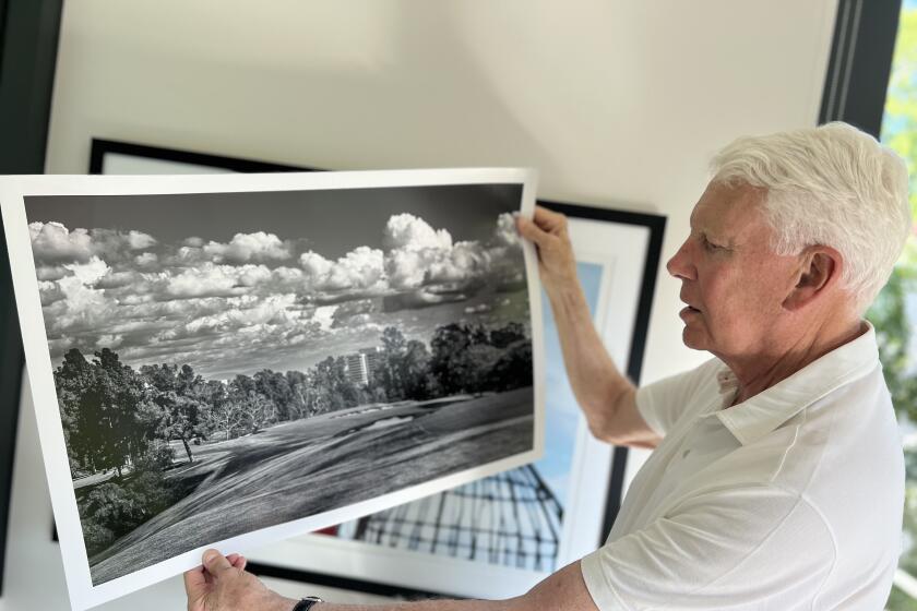 John Light holds up a black and white photograph he took of the 16th hole at Los Angeles Country Club.