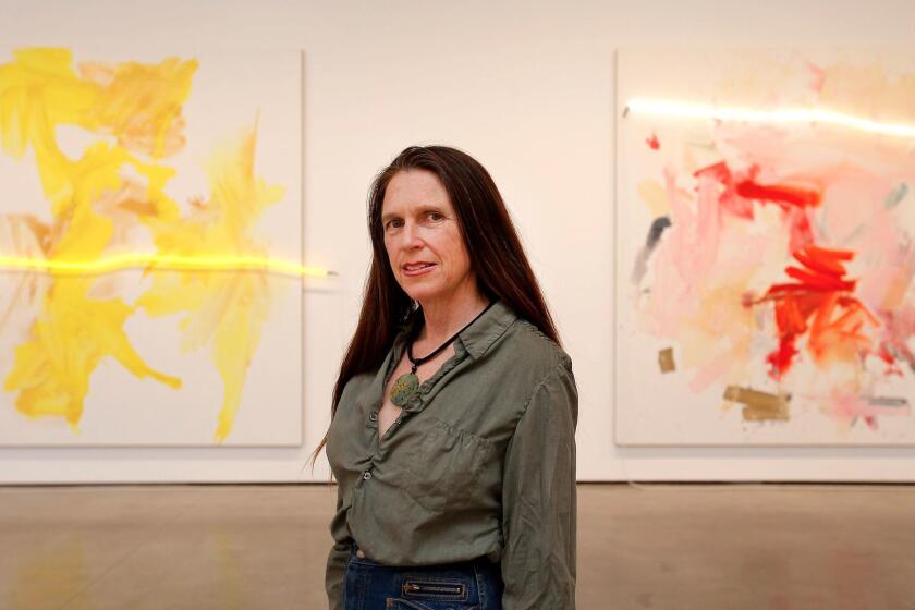 Mary Weatherford, known for creating abstract canvases that feature bright touches of neon, stands before "Daisy," left, and "Rosalita" at David Kordansky Gallery.