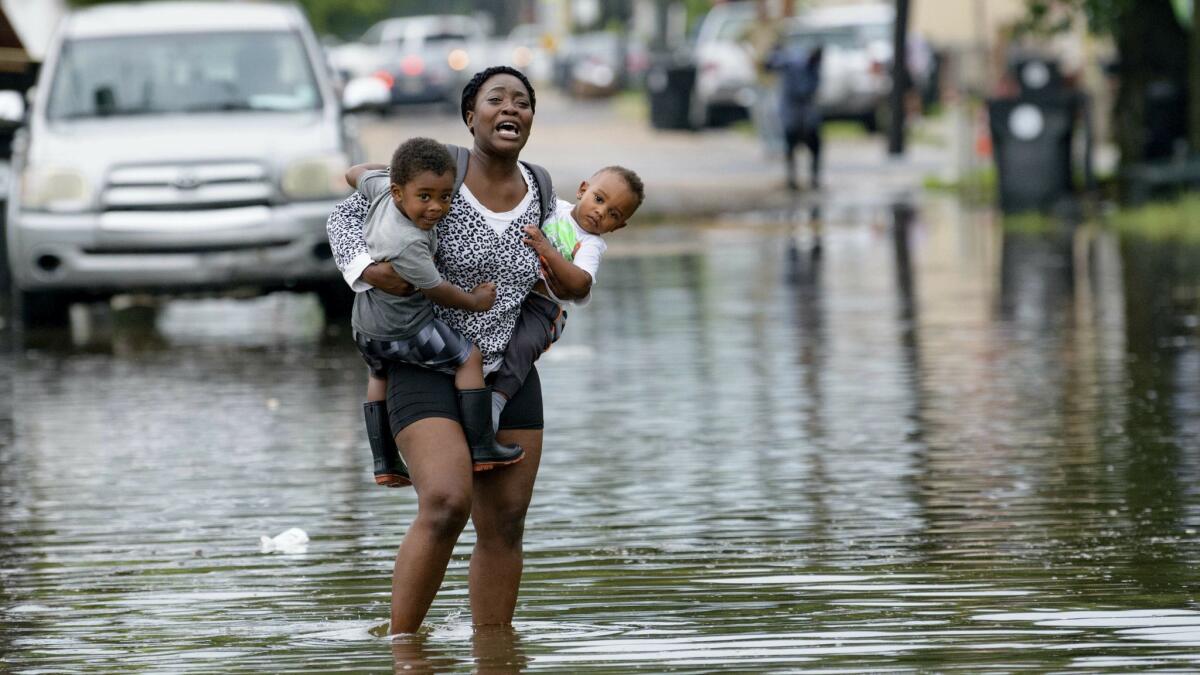 Terrian Jones carries Drew and Chance Furlough to their mother on Belfast Street in New Orleans during flooding Wednesday.