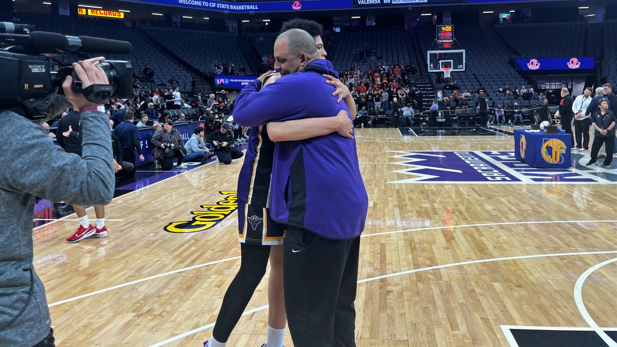 Valencia boys' basketball coach Bill Bedgood hugs his son, Bryce, after the Vikings won the Division IV state title Saturday.