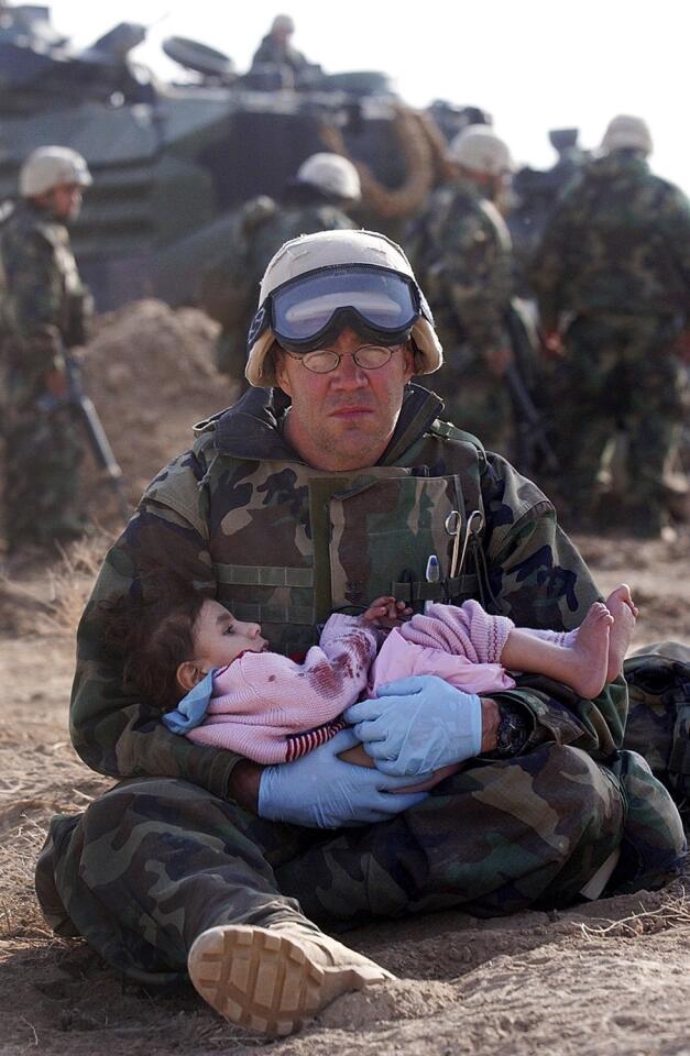 Navy Corpsman Richard Barnett holds an Iraqi boy in shock after his mother was killed from the crossfire between Marines and Iraqi soldiers. March 29, 2003.