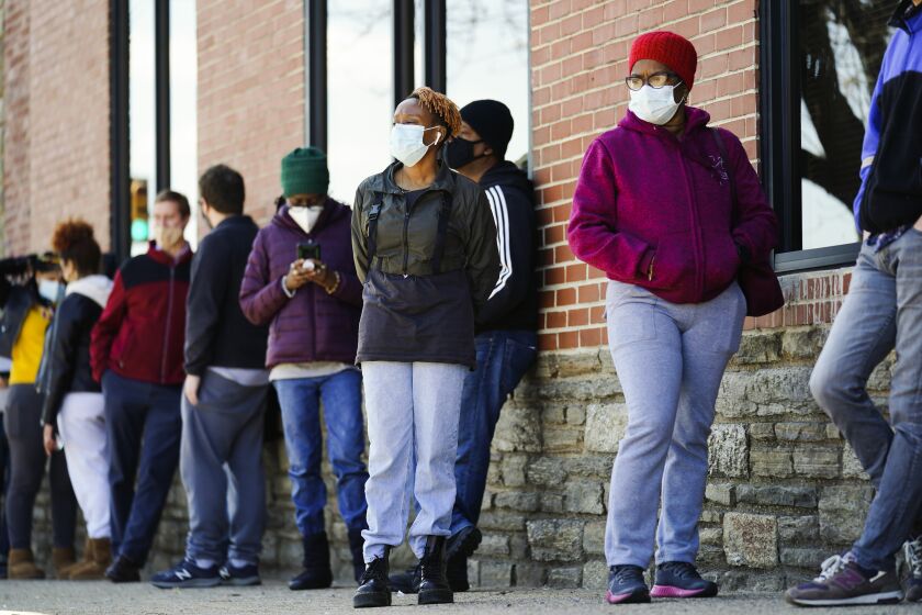 FILE - In this March 29, 2021, file photo, people wearing face masks as a precaution against the coronavirus wait in line to receive COVID-19 vaccines at a site in Philadelphia. Nearly half of new coronavirus infections nationwide are in just five states, including Pennsylvania — a situation that puts pressure on the federal government to consider changing how it distributes vaccines by sending more doses to hot spots. (AP Photo/Matt Rourke, File)