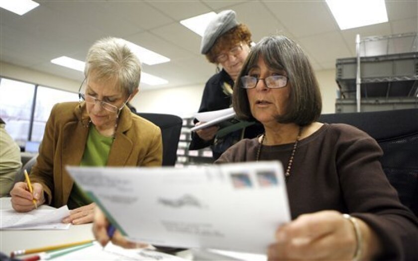 Division of Election workers Margaret Campizi, right, and LouAnne Culey, left, validate mail-in ballots as Iyllamae Olsonoski, with the Sen. Ted Stevens campaign, center, watches at the Office of Elections in Anchorage, Alaska on Friday Nov. 14, 2008. About 12 percent of ballots in the general election are still to be counted with Democrat Mark Begich leading 814-votes over Stevens. (AP Photo/Al Grillo)
